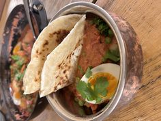 two tacos and an egg in a bowl on a table