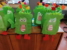 some paper bags with plants on them and flowers sticking out of the top, sitting on a table