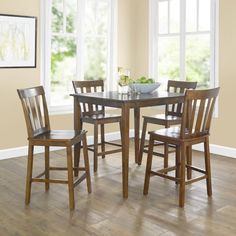 a kitchen table with four chairs and a bowl of fruit