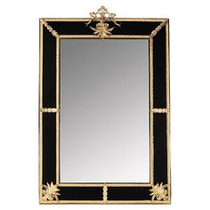 a black and gold mirror with an ornate design on the bottom, in front of a white background