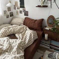 an unmade bed in a bedroom with lots of pictures on the wall and floor