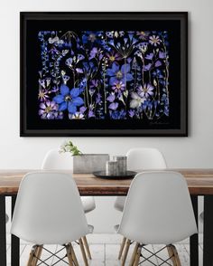 two white chairs sitting at a wooden table in front of a painting on the wall