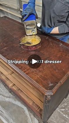 a person in blue gloves sanding a wooden table with a grinder on it