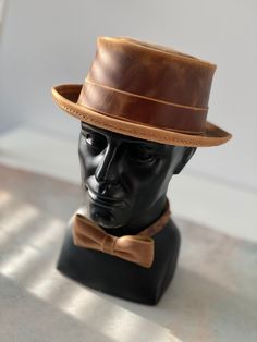 Add a touch of vintage style to your outfit with this handmade pork pie hat and bow tie set, crafted from genuine Crazy Horse leather.  This set is perfect for: - Special occasions such as weddings, proms, and formal events - Adding a touch of sophistication to your everyday look - A unique and thoughtful gift for the man in your life HAT SIZE: We will sew a hat, especially for you, according to the size of your head. How to know your size? Measurements should be made directly above the ears - this will be a conditional line of the landing of your hat.  Repeat the measurement several times - around the widest part of the head.  The head circumference in centimeters will be the size of your hat. BOW TIE SIZE: 4,7 x 2.4 inch (12cm x 6cm) The bow tie has an adjustable strap for a comfortable Classic Brown Top Hat For Kentucky Derby, Classic Brown Top Hat For Formal Occasions, Classic Brown Formal Top Hat, Handmade Vintage High Crown Top Hat, Classic Brown Handmade Hat, Adjustable Brown Top Hat For Kentucky Derby, Fitted Brown Boater Hat With Flat Crown, Formal Adjustable Top Hat With Flat Bill, Formal Brown Brimmed Top Hat