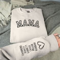 Personalized Mama Sweatshirt with Kid Names on Sleeve, Personalized Mama Gift, Birthday Gift for Mom, New Mom Gift, Minimalist Cool Mom Sweater Our mama sweatshirt is the perfect gift for all moms! The shirt will leave mama feeling cozy yet chic every day. Personalize the left or right sleeve with the names of the mother's children and/or loved ones to make it even more special. I T E M ∙ D E T A I L S * Crewneck Sweater, 50% cotton, 50% polyester * Unisex Sizing: S, M, L, XL, 2XL Sweatshirt:  Gildan 18000, Ideal for any situation, a unisex heavy blend crewneck sweatshirt is pure comfort. These garments are made from polyester and cotton. This combination helps designs come out looking fresh and beautiful. The collar is ribbed knit, so it retains its shape even after washing. There are no Mama Sweaters, Mama Sweater Cricut, Custom Mama Sweatshirts, Mama Shirts Sweatshirts & Hoodies, Mother's Day Personalized Crew Neck T-shirt, Mama Sweater, Birthday Gift For Mom, Mom Sweater, Cool Mom