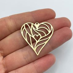 a hand holding a gold heart shaped brooch