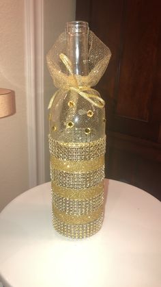 a clear bottle with gold sequins and a bow on top sitting on a table