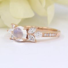 a close up of a ring on a white surface with flowers in the back ground