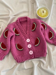 a pink knitted sweater with watermelon slices on it and a bowl of dip