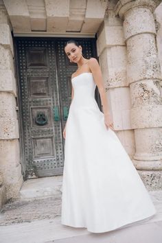 a woman standing in front of a door wearing a white dress