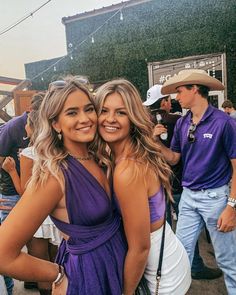 two beautiful young women standing next to each other in front of a group of people