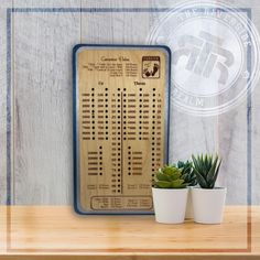 a wooden board with numbers on it next to two potted succulents