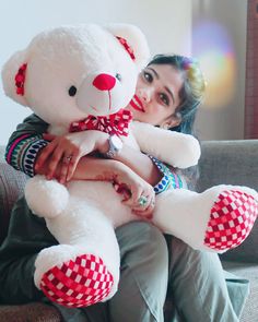 a woman sitting on a couch holding a large white teddy bear