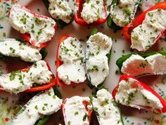 several peppers with cheese and herbs on them sitting on a white plate next to confetti sprinkles