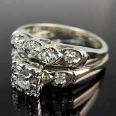 two wedding rings sitting on top of each other with diamonds in the middle and sides