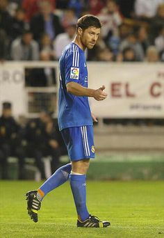 a soccer player walking on the field with his foot in the air and people watching from the stands