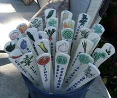 many spoons with different types of vegetables on them are in a blue cup outside