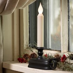 a white candle sitting on top of a window sill