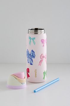 a pink cup with bows on it next to a blue and white toothbrush holder