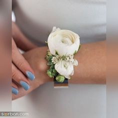 a woman's arm with a white flower and greenery on it, while wearing a ring