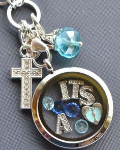 a key chain with a cross and two charms on it that says, its's a boy