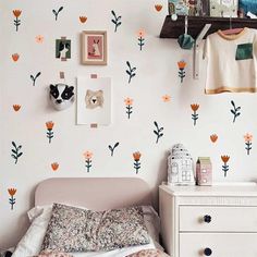 a bed room with a neatly made bed next to a white dresser and wall mounted pictures