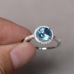 Here is a gorgeous blue topaz ring set in solid sterling silver and with rhodium plated. The ring features a 7mm faceted round clear swiss blue topaz and lots of tiny zircon around the main stone. The item is sent in a beautiful gift box You can realize more lovely stuff clicking the link https://www.etsy.com/shop/knightjewelry?refshopsection_shophome_leftnav Sapphire Topaz Round Ring For Promise, Sapphire Topaz Promise Ring, Sapphire Topaz Ring For Promise, Blue Topaz Birthstone Diamond Ring With Round Cut, Round Cut Blue Topaz Birthstone Diamond Ring, Light Blue Round Sapphire Promise Ring, White Gold Cubic Zirconia Topaz Birthstone Ring, Light Blue Topaz Ring With Round Cut, Light Blue Brilliant Cut Topaz Ring For Gift