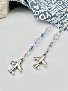 a pair of earrings with an airplane charm hanging from it's earwires