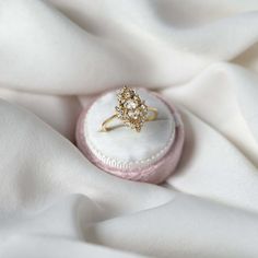 an engagement ring sits on top of a white cloth