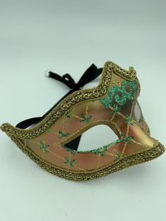 "This is a very nice original handmade and hand painted Venezia masquerade face mask made in Italy. The design on the shiny gold and orange face mask features turquoise blue and multi-color glitter with a border of gold lace and gold rope around the edges. It comes with a black ribbon tie and is stamped on the back \"Original Hand Painted Made in Italy Venezia\". The mask measures approximately 6 5/8\" long and 3 3/4\" wide and is in very good preowned condition with light wear on the back of th Artistic Masks And Prosthetics For Mardi Gras Carnival, Adjustable Masquerade Mask For Mardi Gras, Mardi Gras Masks And Prosthetics, Hand Painted Masks And Prosthetics For Carnival, Hand Painted Masks For Masquerade Carnival, Artistic Masquerade Mask For Mardi Gras Carnival, Hand Painted Masks For Carnival Masquerade, Multicolor Masks And Prosthetics For Masquerade And Carnival, Venetian Full Face Masquerade Mask For Party