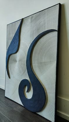 an abstract painting on the wall with blue and white swirls in front of it