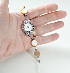 "Mother of pearl sterling silver bracelet watch is handcrafted. Would make a great 50th birthday gift for Mom or Mothers Day gift from son or daughter! Beige shell mother of pearl showcased with white freshwater pearls and Bali sterling silver. Watch is adjustable from 6 1/4\" to 8 1/2\". Metaphysical meaning of Mother of Pearl: Mother of Pearl, considered a protection stone, is a stress relieving stone; relaxing, soothing and calming to the emotions. It stimulates our intuition, imagination, se Vintage Silver Pearl Bracelet Gift, Timeless Silver Pearl Jubilee Bracelet, Classic Silver Pearl Bracelet As Gift, Classic Silver Pearl Bracelet Gift, Silver Bracelet Strap Jewelry For Anniversary, Handmade Silver Pearl Bracelet Gift, Silver Strap Bracelet For Anniversary, Handmade Round Pearl Bracelet For Anniversary, Handmade Pearl Bracelet For Anniversary