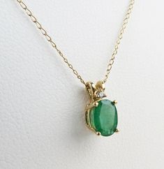 Lovely petite natural green emerald with diamond accent pendant set in 14k yellow gold with a fine matching chain necklace A natural emerald with really nice color and diamond accents dangle on this vintage 14k yellow gold pendant necklace. The oval 1/2 carat faceted emerald measures approx. 6.9mm x 5.1mm x 3mm. It is held tightly with four prongs below one melee diamonds that have a total .004 carat weight. The yellow gold setting compliments the medium green color of the precious emerald. The emerald has expected natural inclusions typical of emerald crystal growth.  The yellow gold setting is hallmarked, "14k" (gold) followed by "P" for Plumb, which is a guarantee of minimum 14k purity. The setting also tested as at minimum 14k gold. The pendant hangs from a sturdy bail and matching yel Classic Green Emerald Necklace With Diamond Accents, Formal Green Emerald Necklace In 14k Gold, Green Pendant Necklace With Prong Setting, Green Pendant Necklaces With Prong Setting, Classic Green Emerald Necklace In 14k Gold, Classic Green Diamond Pendant Necklace, Green Emerald Diamond Pendant Necklace, Classic Green Pendant Diamond Necklace, 14k Gold Green Necklace With Diamond Accents