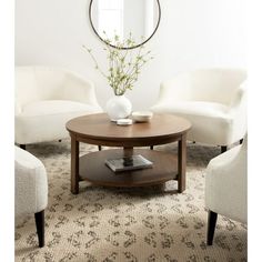 a living room with two chairs and a coffee table in front of a round mirror