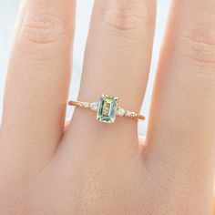 a woman's hand with an emerald and diamond ring on top of her finger