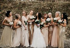 a group of women standing next to each other wearing dresses and holding bouquets in their hands