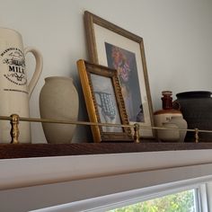 there are vases and pictures on the shelf above the window sill in this room