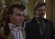 two men standing next to each other in front of a christmas tree, one wearing a bow tie