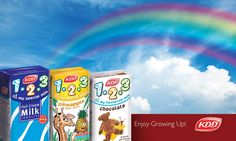 three boxes of milk are in front of a rainbow and blue sky with white clouds