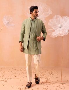 An open embroidered nehru jacket adorned with dori buttons, paired harmoniously with a tonal kurta and white pants ensemble. Luxury Classic Nehru Jacket, Designer Sherwani For Spring, Spring Wedding Nehru Jacket With Traditional Drape, Fitted Bandhgala With Traditional Drape For Spring, Designer Cotton Bandhgala For Eid, Spring Wedding Bandhgala With Traditional Drape, Cotton Nehru Jacket With Cutdana And Long Sleeves, Designer Wear Spring Kurta With Set-in Sleeves, Designer Spring Kurta With Set-in Sleeves