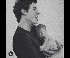 a black and white photo of a man holding a baby in his arms, smiling