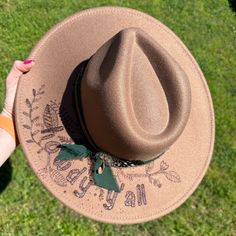 Turn heads wherever you go with this fun and stylish hat! What a fun piece to add to your wardrobe! This light brown hat features the saying  "howdy y'all"  with a floral surrounding. The saying and floral designs are hand burned. Premium Quality Branded Wide Brim Hats Each hat is hand burned. The hat pictured is the hat you will receive.  Vegan felt fedora hat Wide, stiff, flat brim. Stylish hat, wedding, everyday hat Structured wide brim panama hat in vegan felt. Flat and stiff brim Adjustable inner drawstring Crown size: 57 cm Brim: 4 in. 65% polyester 35% Cotton : This combination offers durability, comfort, and easy maintenance. Due to various sanitary concerns, hats are not returnable or exchangeable. Trendy Hats For Kentucky Derby Festival, Trendy Hats For Kentucky Derby, One Size Fits Most, One Size Fall Hat With Short Brim, Wide Brim Outdoor Hat One Size, Outdoor Wide Brim Hat One Size, Flat Brim Festival Hat For Fall, Wide Brim Hats For Outdoor, Casual Felt Hat For Festivals, Adjustable Hat For Kentucky Derby