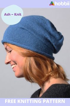 a woman with red hair wearing a blue knitted hat and smiling at the camera