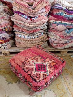 a pile of blankets sitting on top of a floor next to a box filled with pillows