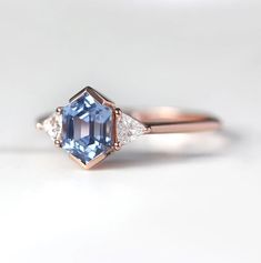 a blue and white diamond ring with three diamonds on the side, set in rose gold