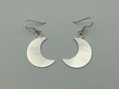 I've designed a pair of crescent moon earrings, 1 1/8 inches each in size, with dangling ear hook wires. The set is completely handmade in sterling silver. Inspired by Stevie Nicks, I wanted to fabricate matching earrings to the moon pendant and as this was for a customer request, I thought, what a grand idea! I can offer a 24K gold plating option that I will include in the drop down menu at checkout! The last image is to show the crescent moon necklace. Please convo for any questions! Allow me Modern Crescent Jewelry For Pierced Ears, Elegant Half Moon Nickel Free Earrings, Modern Crescent Jewelry With Ear Wire, Modern Moon Shaped Earrings For Gift, Crescent Moon Charm Earrings As Gift, Nickel Free Minimalist Half Moon Earrings, Elegant Half Moon Nickel-free Earrings, Silver Half Moon Earrings With Sun And Moon Design, Silver Teardrop Earrings With Moon Charm