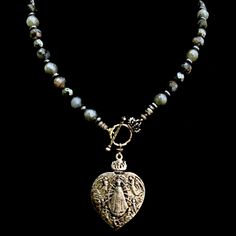 The Lujan Choker features an intricately carved Our Lady of Lujan medal within a flaming Sacred Heart made of Sterling Silver. She's surrounded by Angels, with two of them raising a crown of flowers above her. Pilgrims worldwide travel to see Her and have received special graces, favors and miracles. The gunmetal linked chain is offered in 17" or 22" based on your preference. If you need a longer or shorter size we can make one for you. It's a very special necklace because of the rarity of the m Surrounded By Angels, Crown Of Flowers, Special Necklace, Wrap Necklaces, Sacred Heart, Our Lady, Rarity, Are You The One, Necklaces Bracelets