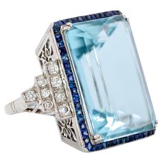 Impressive Emerald Cut Aquamarine surrounded by French Cut Sapphires and Diamond Ring Eleanor is named for Former First Lady Eleanor Rosevelt, who received a stunning 1,298 Carat Aquamarine from President Vargas of Brazil in 1936. What a gift! Brazil continues to produce the finest quality Aquamarines just as you will find in our "Eleanor." An unbelievable piece from another era assured to make you feel like an iconic movie star! This exquisite ring boasts a 45.41 Carat Emerald Step Cut Aquamari Luxury Octagon Ring With Gemstone Accents, Formal Multi-stone Rectangular Ring, Elegant Rectangular Multi-stone Rings, Elegant Multi-stone Rectangular Rings, Art Deco Sapphire Ring With Accent Stones, Formal Octagon Multi-stone Rings, Exquisite Octagon Formal Rings, Formal Multi-stone Octagon Rings, Exquisite Octagon Ring For Formal Occasions