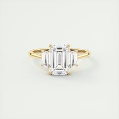 an emerald cut engagement ring with three baguets in yellow gold and white diamonds