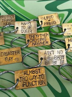 several metal key chains with different sayings attached to them on a green and white background